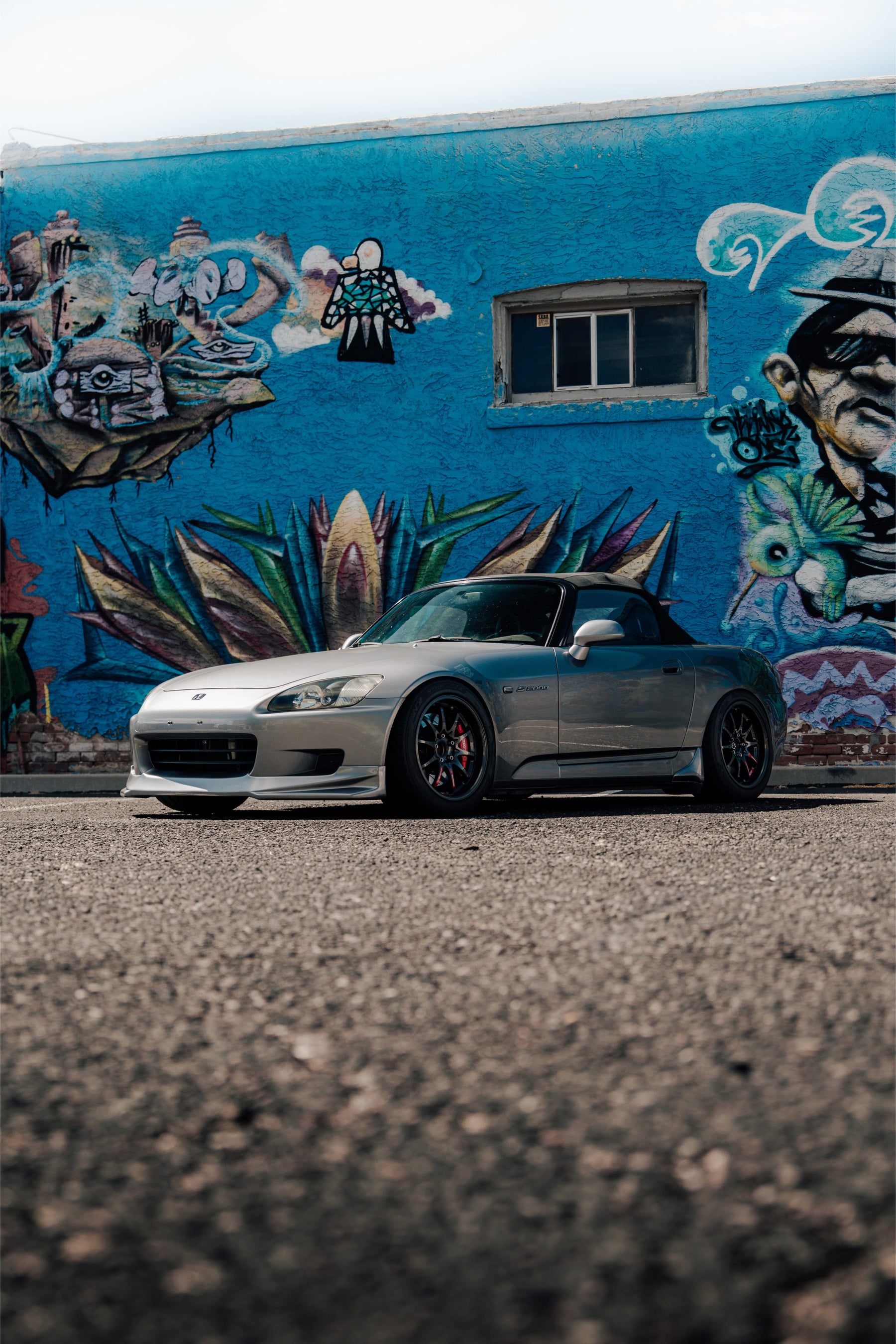 Silver Honda AP1 S2000 parked in front of a mural
