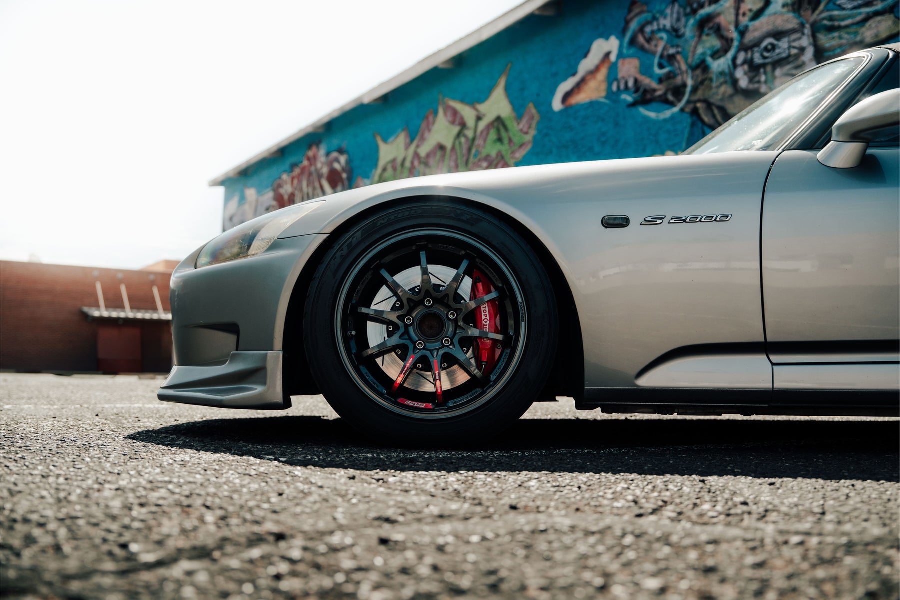 Silver Honda AP1 S2000 parked in front of a mural