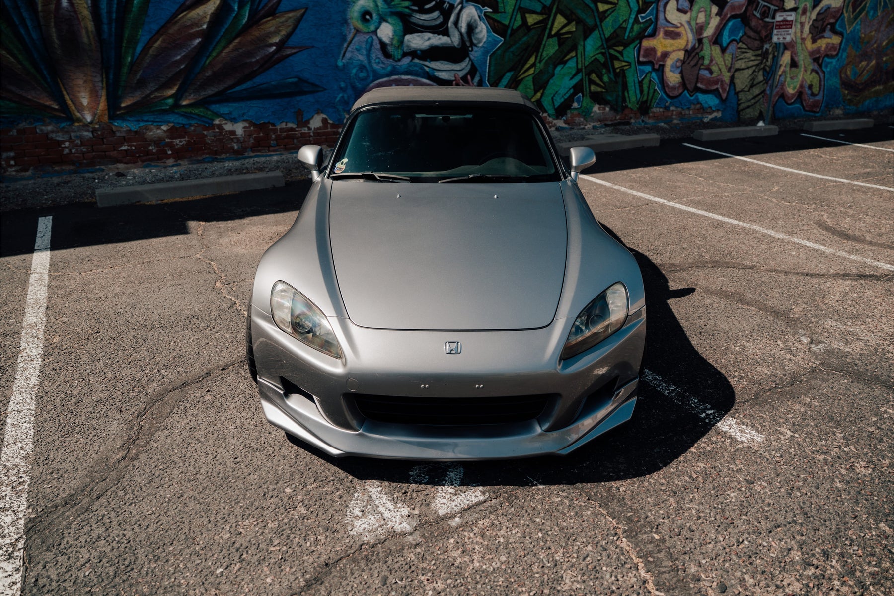 Silver Honda AP1 S2000 parked in front of a mural